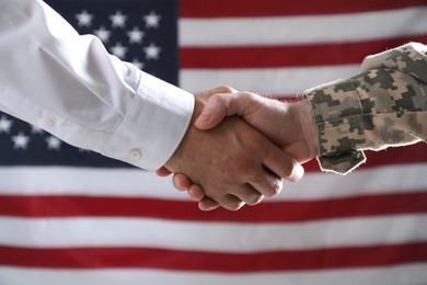 Soldier and businessman shaking hands against flag of USA, closeup