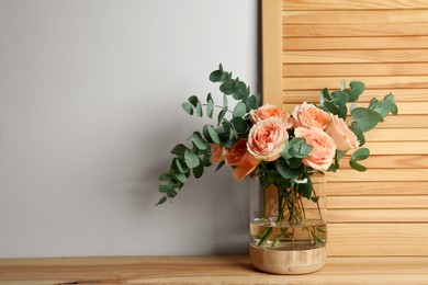 Bouquet with beautiful flowers in glass vase on wooden table. Space for text