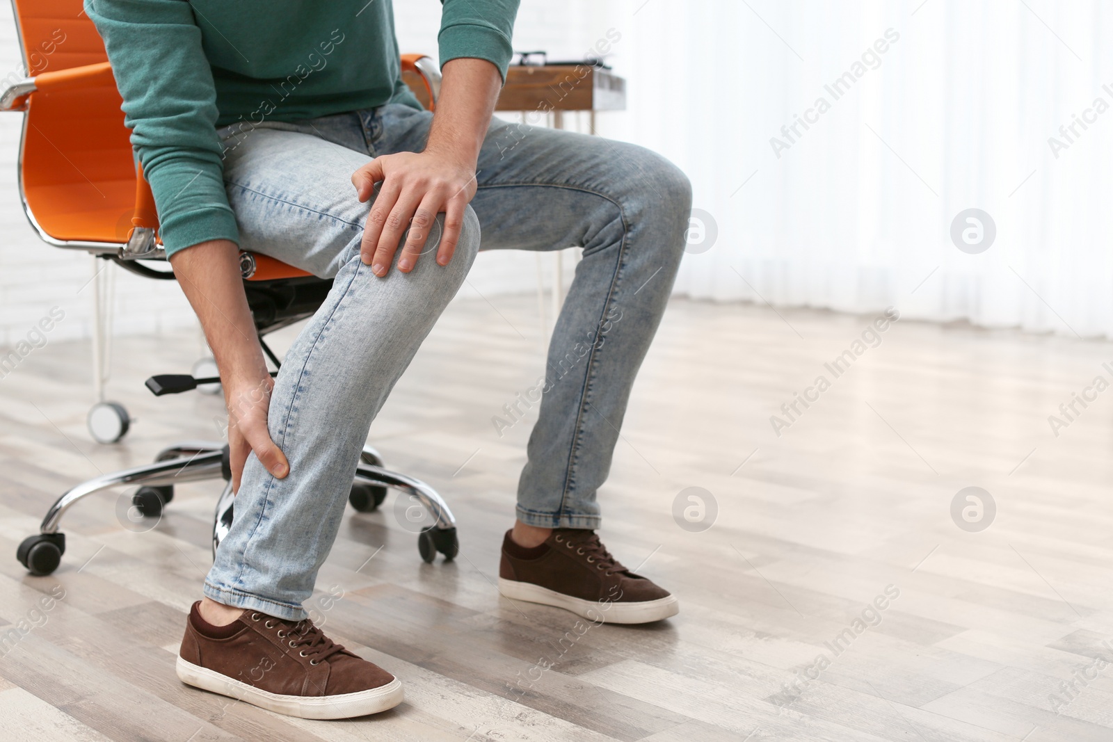 Photo of Man suffering from leg pain indoors, closeup