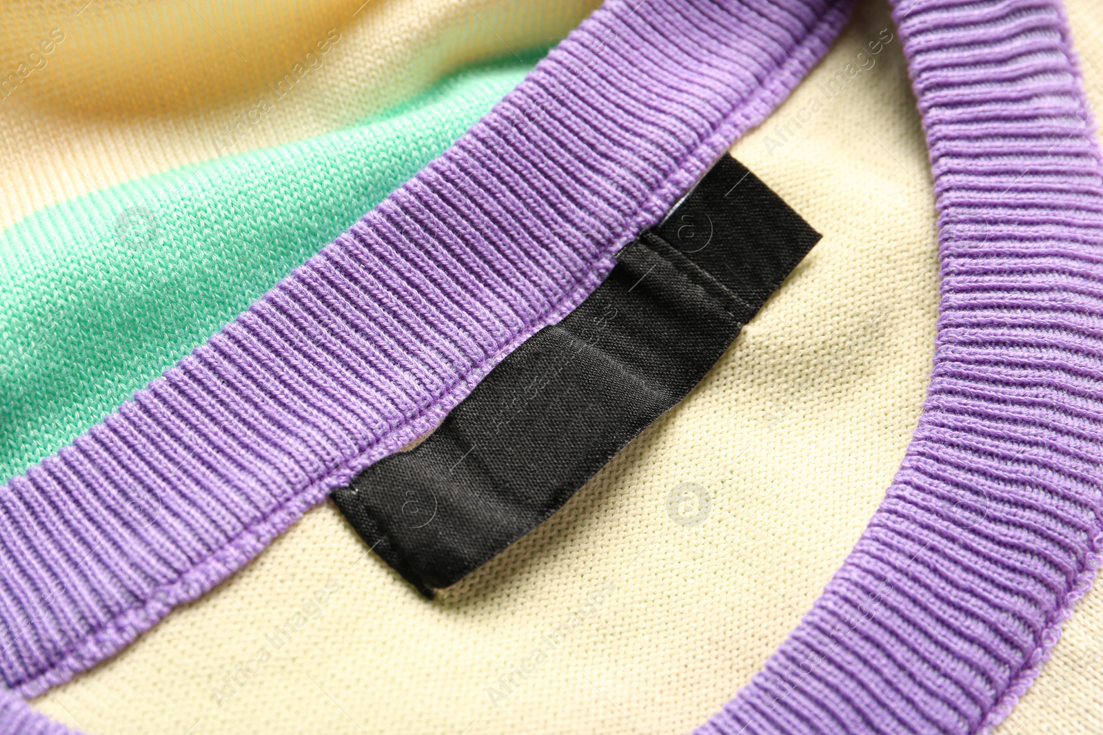 Photo of Blank clothing label on stylish sweater, closeup