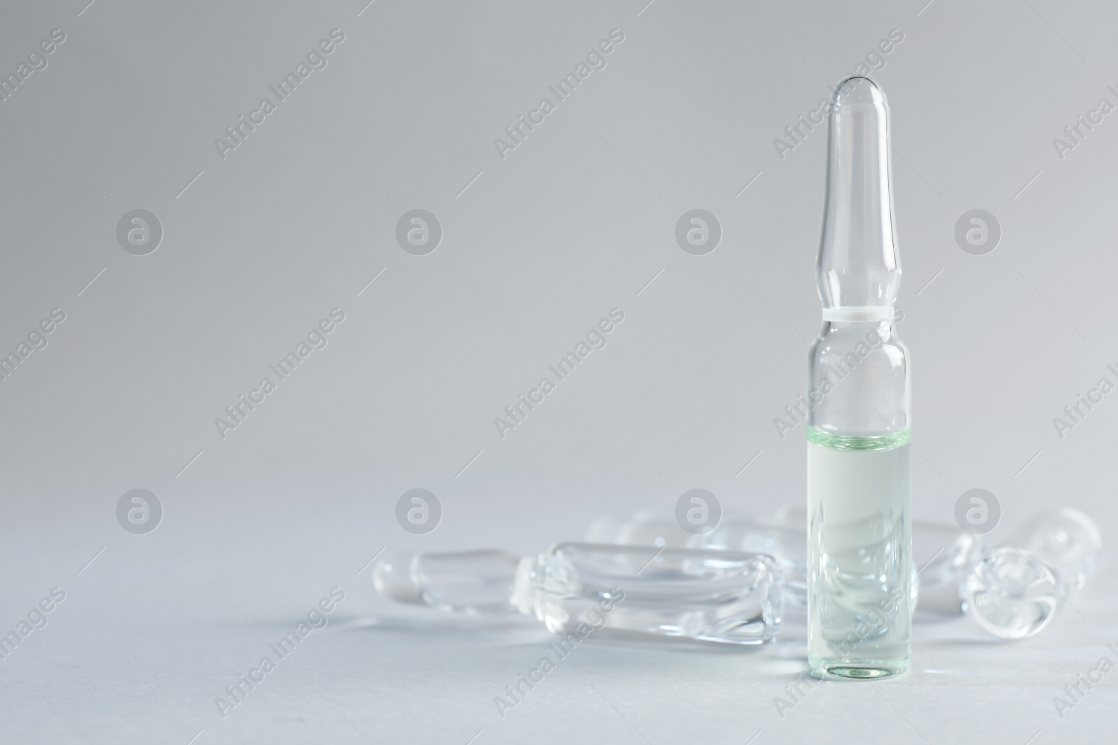 Photo of Pharmaceutical ampoules with medication on light grey background. Space for text