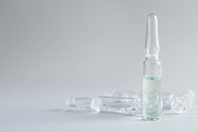 Photo of Pharmaceutical ampoules with medication on light grey background. Space for text