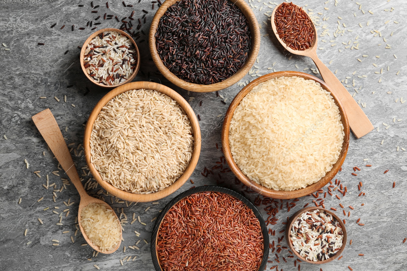 Photo of Flat lay composition with brown and other types of rice on grunge background