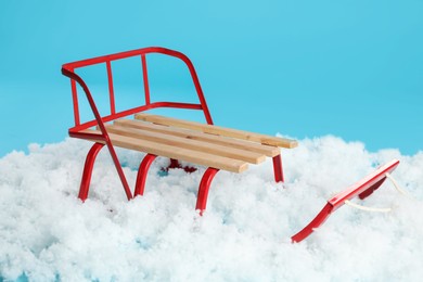 Photo of Sleigh and artificial snow on light blue background. Winter outdoor activity