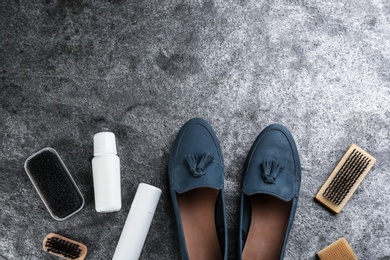 Photo of Stylish footwear with shoe care accessories on grey stone table, flat lay. Space for text