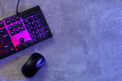 Photo of Modern RGB keyboard and mouse on grey table, flat lay. Space for text