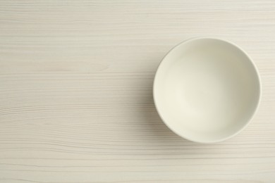 Stylish empty ceramic bowl on white wooden table, top view and space for text. Cooking utensil
