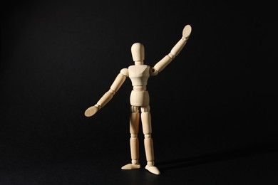 Photo of Wooden human model on black background. Mini mannequin