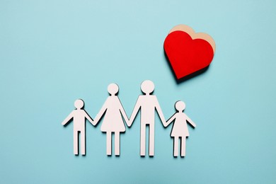 Photo of Figures of family and heart on light blue background, top view. Insurance concept