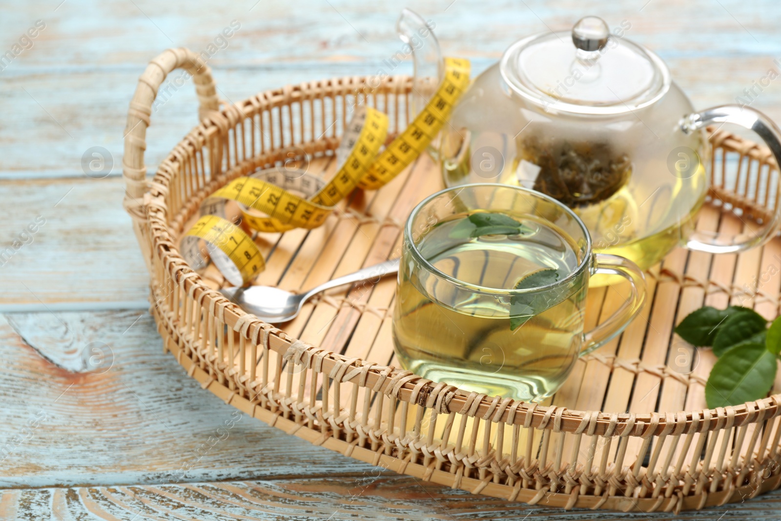 Photo of Diet herbal tea with green leaves on wooden table