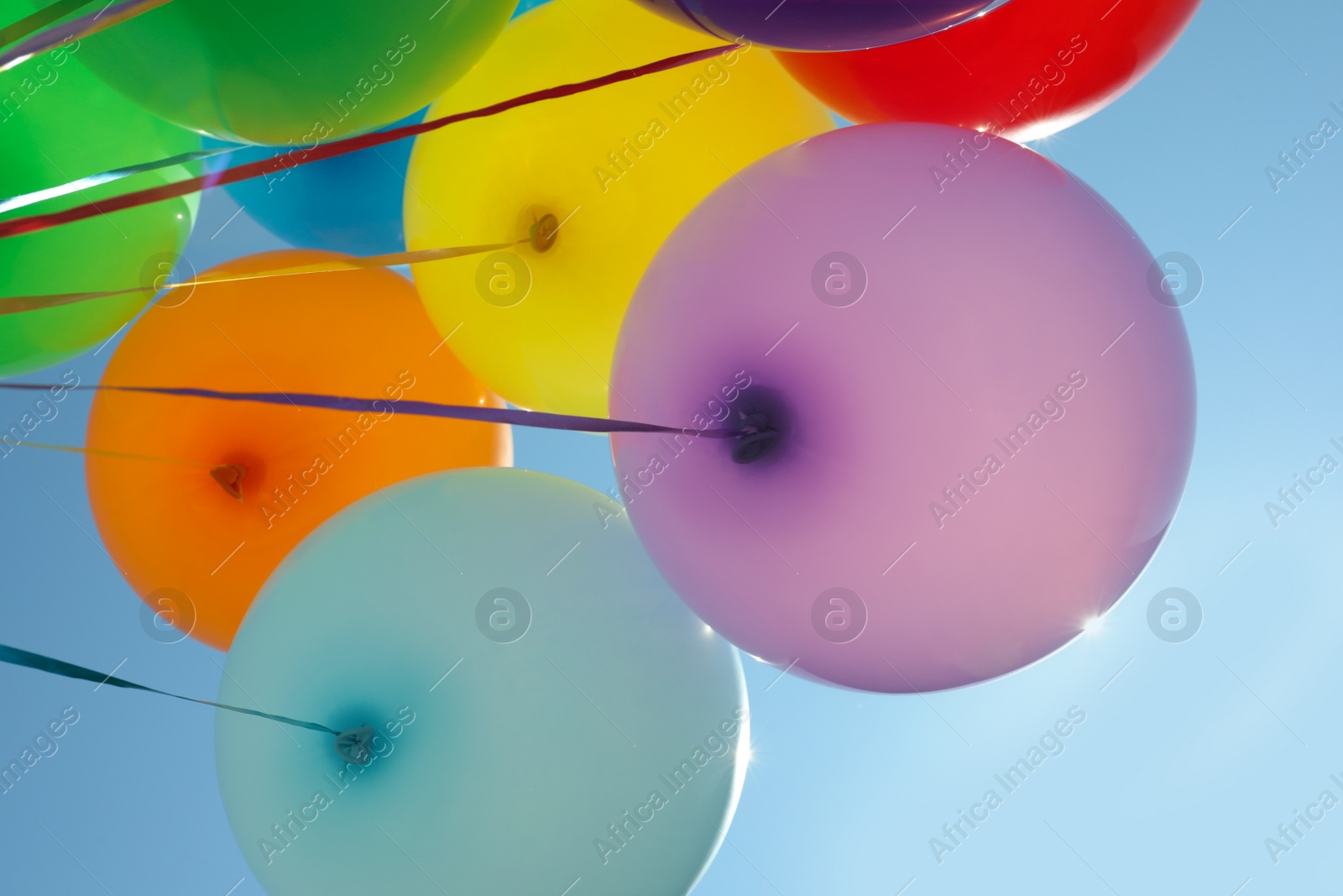 Photo of Bunch of colorful balloons against blue sky, low angle view