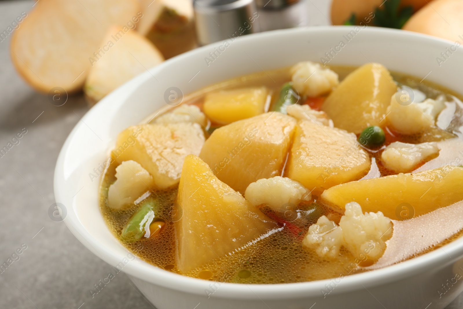 Photo of Bowl of delicious turnip soup on light grey table, closeup