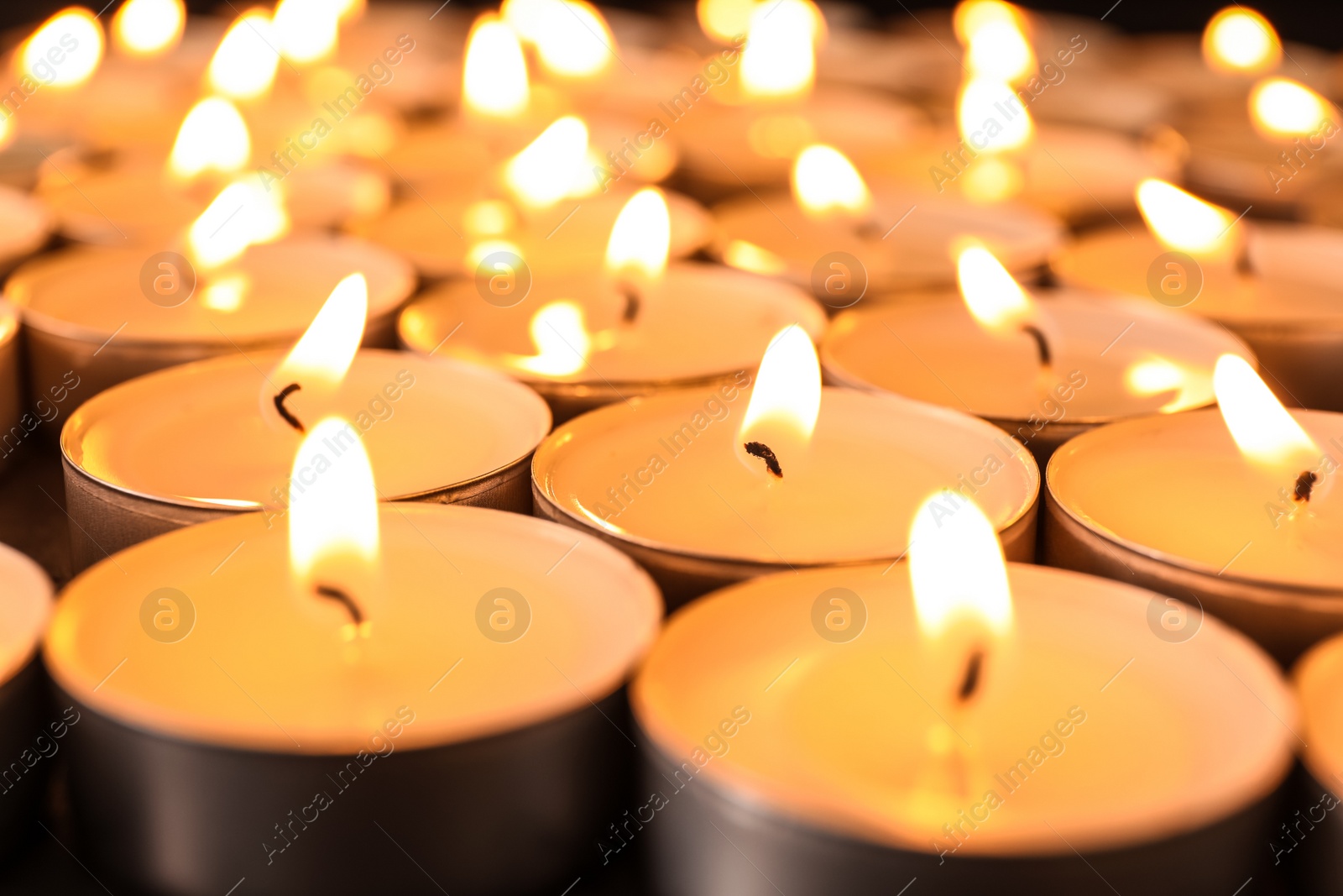 Photo of Many burning candles on table, closeup. Symbol of sorrow