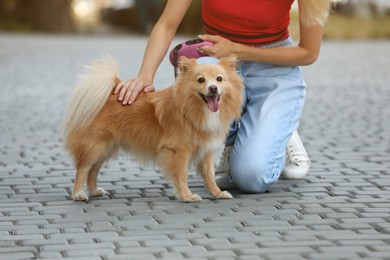 Photo of Young woman with her cute dog on city street, closeup