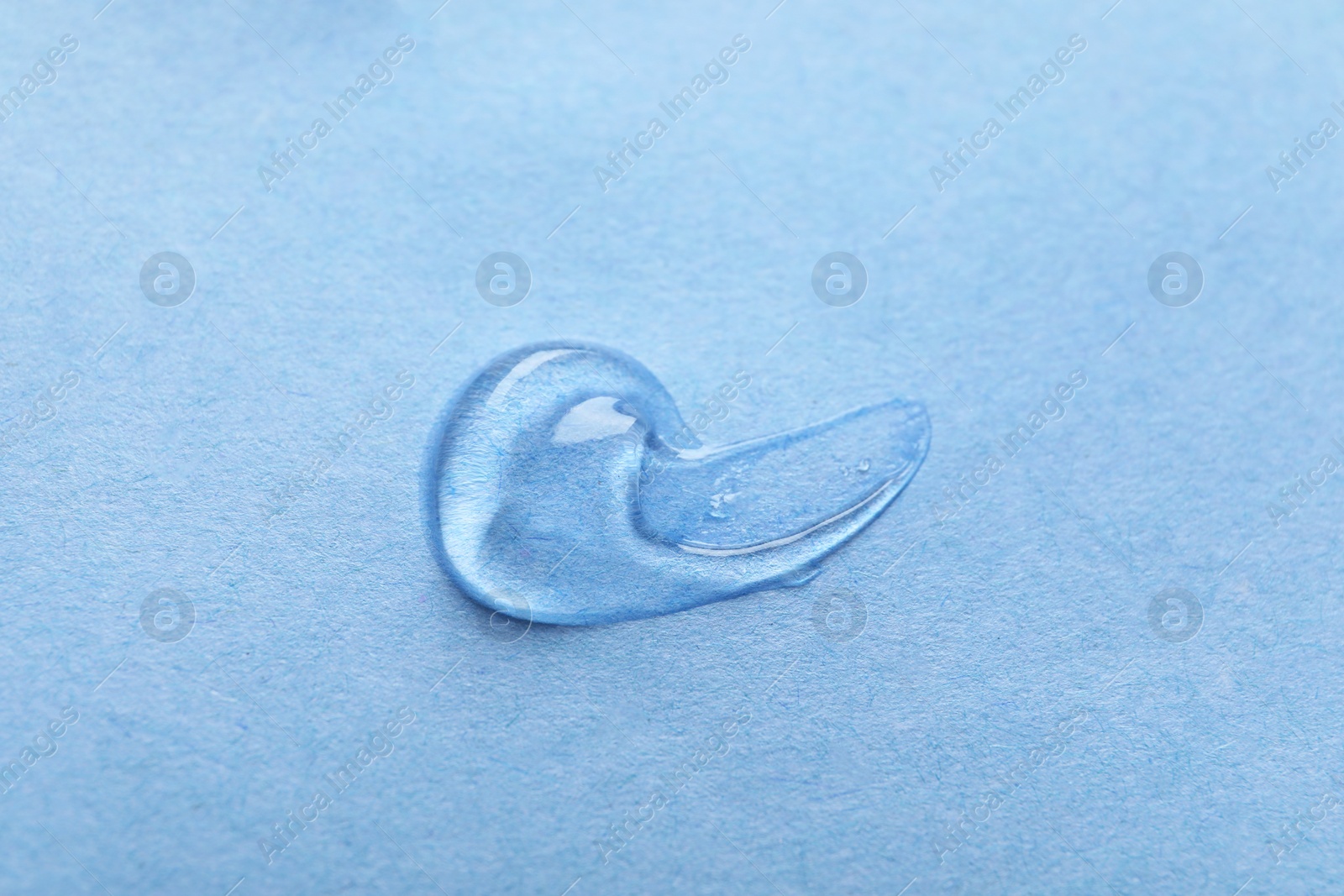 Photo of Sample of transparent gel on light blue background, closeup