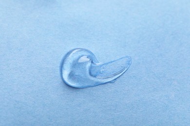 Photo of Sample of transparent gel on light blue background, closeup