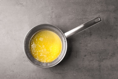 Photo of Saucepan with melting butter on grey table, top view