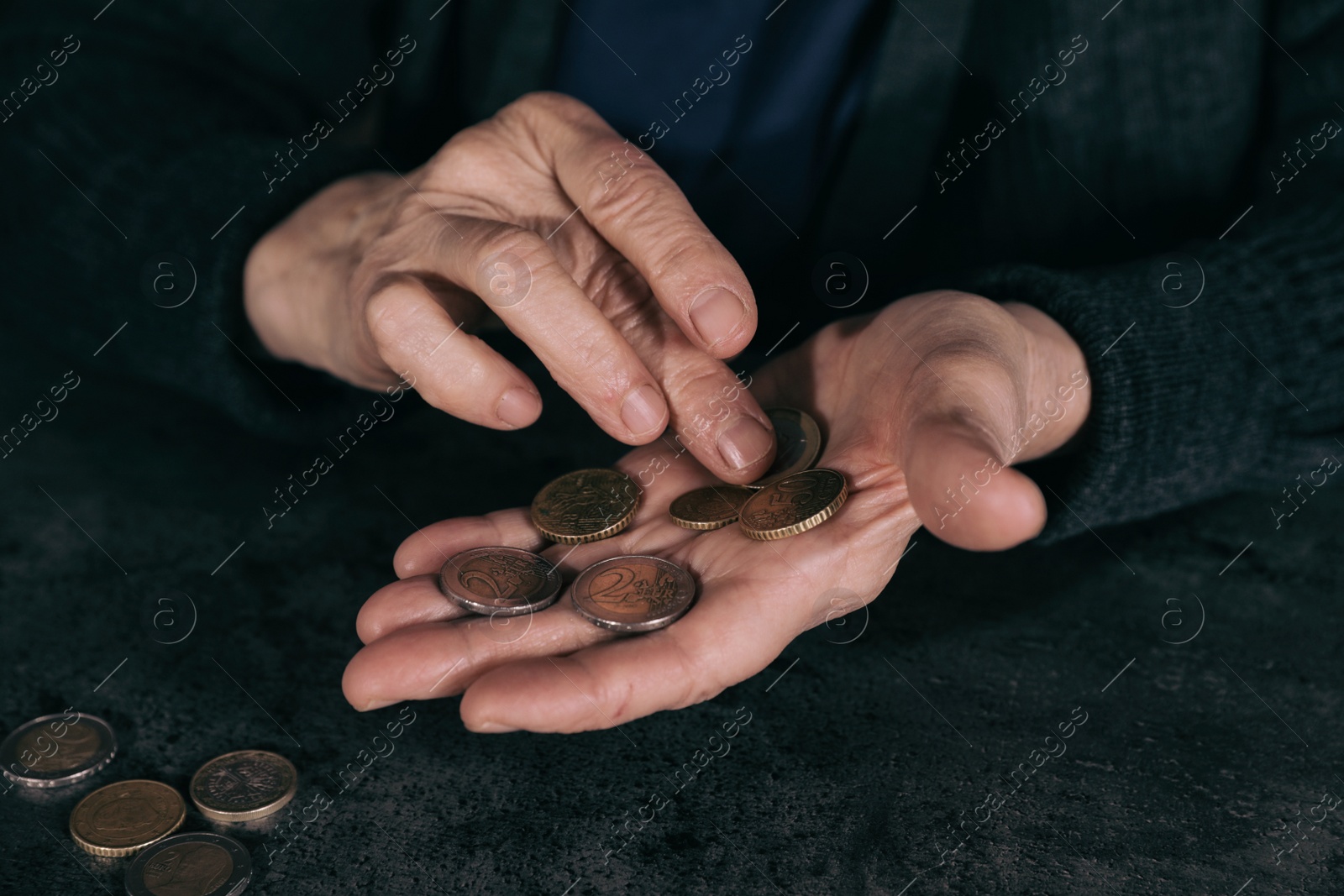 Photo of Poor mature woman counting coins at table, closeup