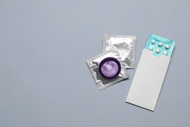 Photo of Contraception choice. Pills and condoms on grey background, flat lay. Space for text