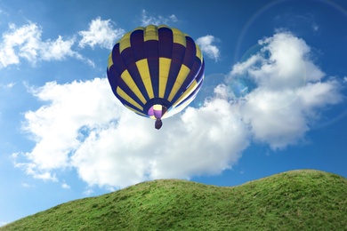 Image of Dream world. Hot air balloon in blue sky with clouds over green hills