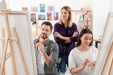 Photo of Artist teaching her students to paint in studio. Creative hobby