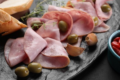 Photo of Tasty ham with olives, garlic and bread on table, closeup