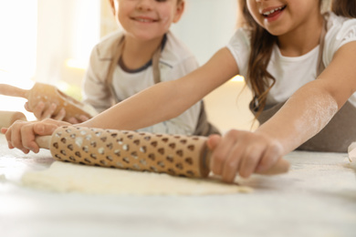 Photo of Cute little children cooking dough together in kitchen, closeup