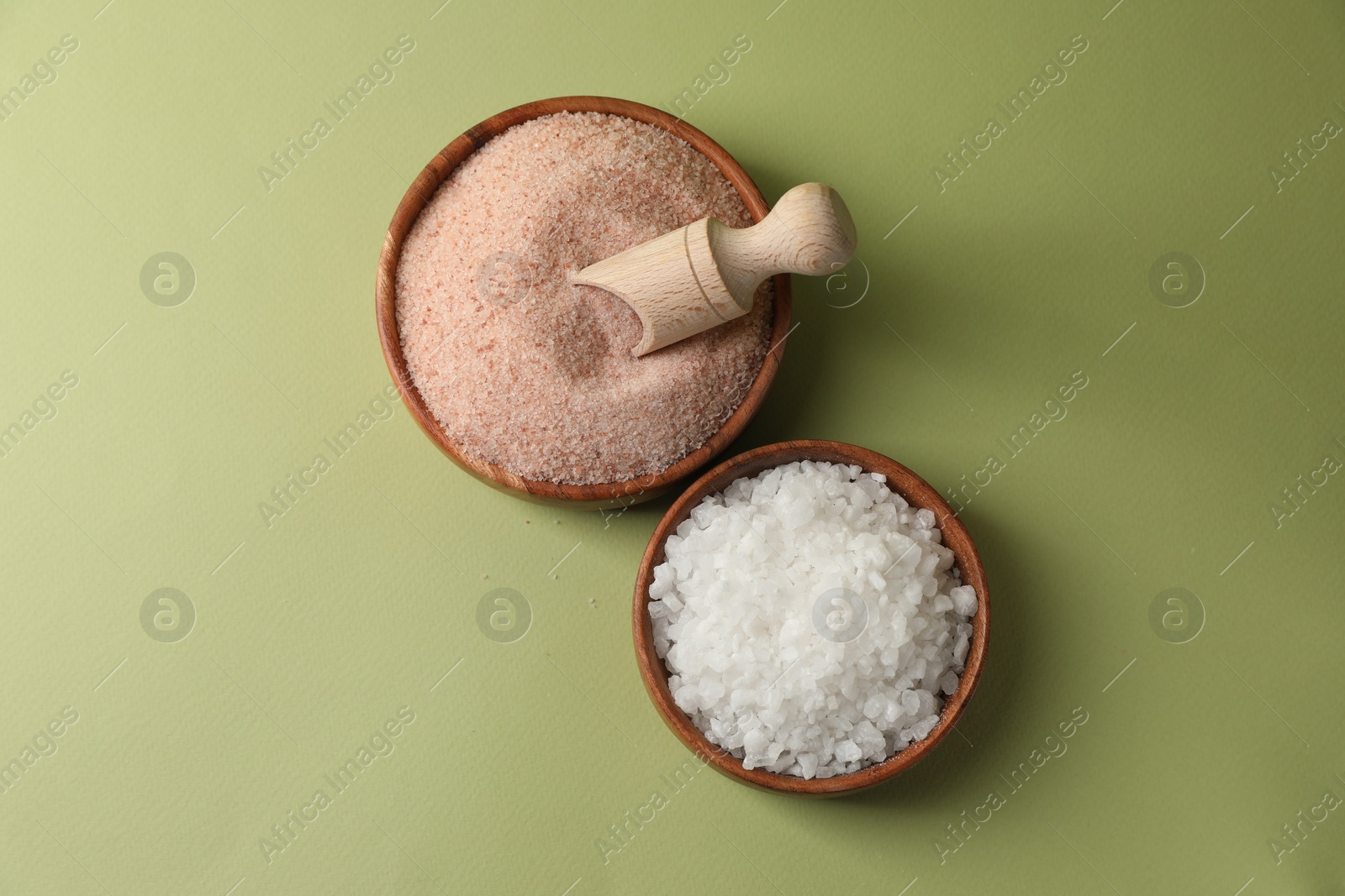 Photo of Different natural salt on green background, flat lay