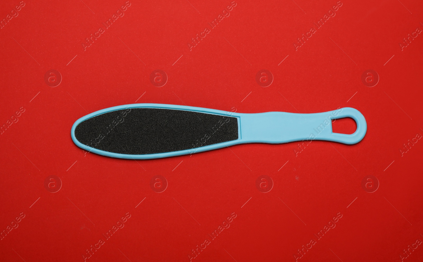 Photo of Light blue foot file on red background, top view. Pedicure tool