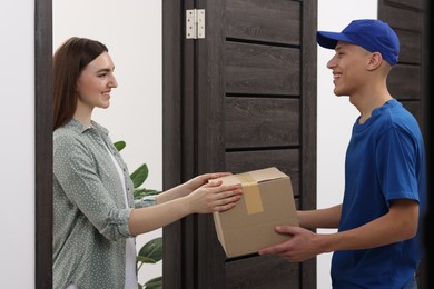 Happy courier giving parcel to receiver indoors