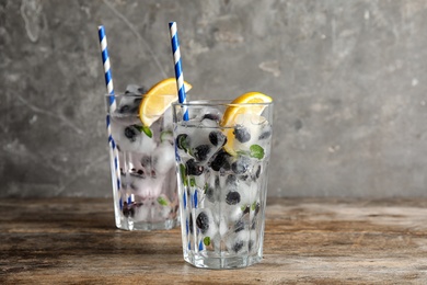 Photo of Glasses of drink with blueberry ice cubes on table. Space for text