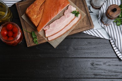 Photo of Flat lay composition with delicious smoked bacon on black wooden table, space for text