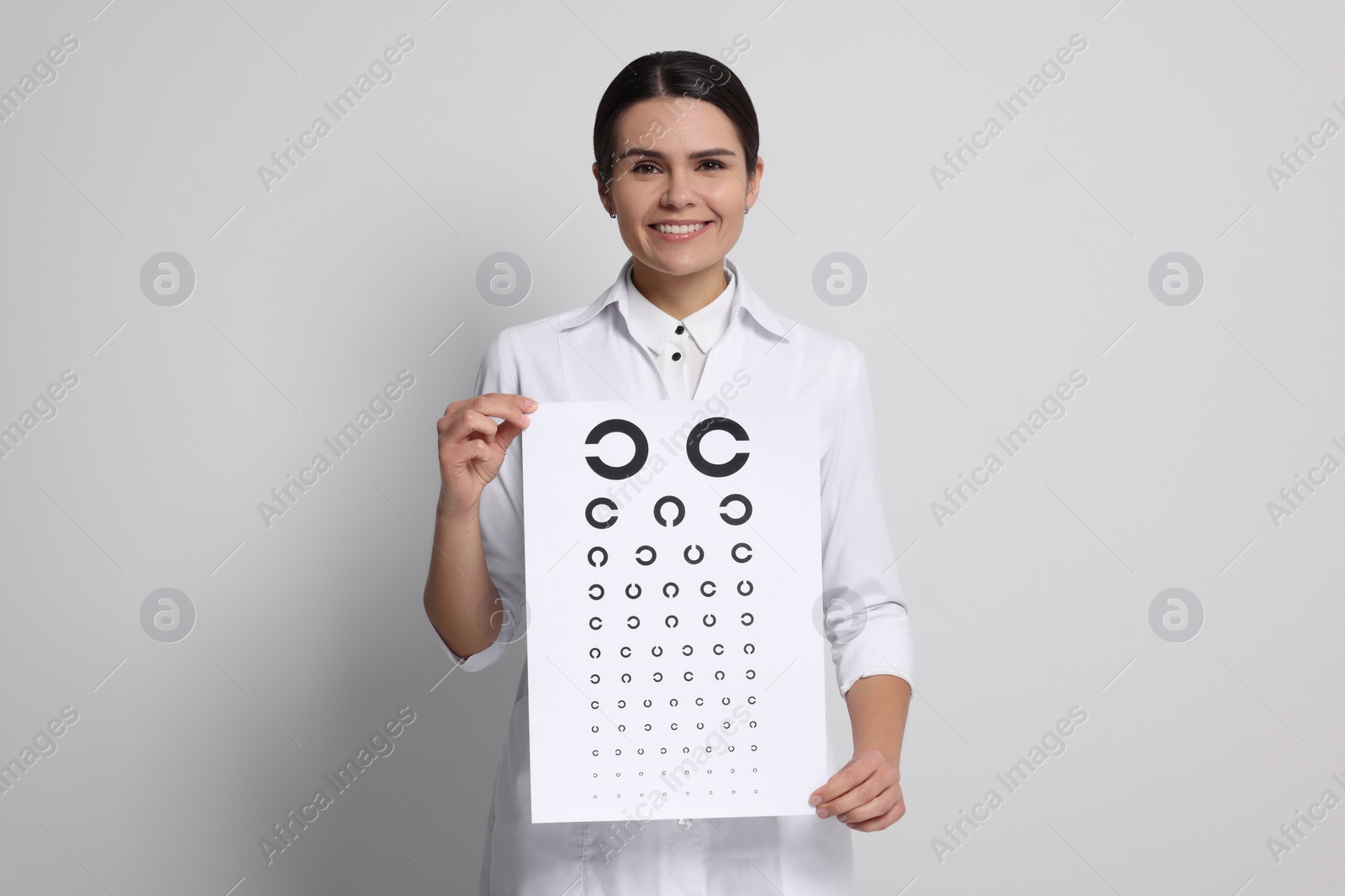 Photo of Ophthalmologist with vision test chart on light background