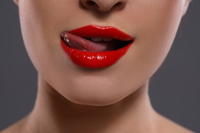Photo of Young woman with red lips makeup on grey background, closeup