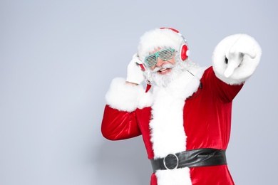 Santa Claus listening to Christmas music on color background