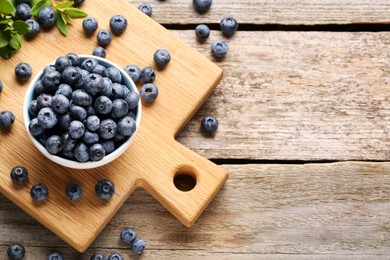 Photo of Tasty fresh blueberries on wooden table, flat lay. Space for text