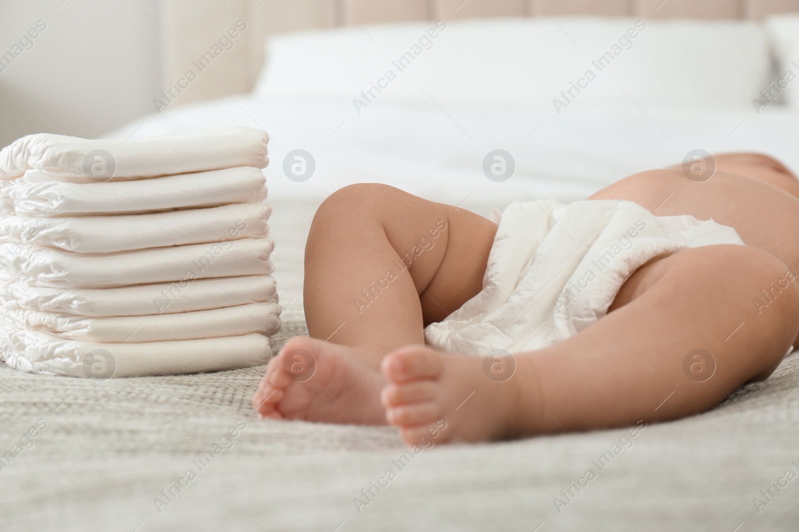 Photo of Cute little baby in diaper on bed at home