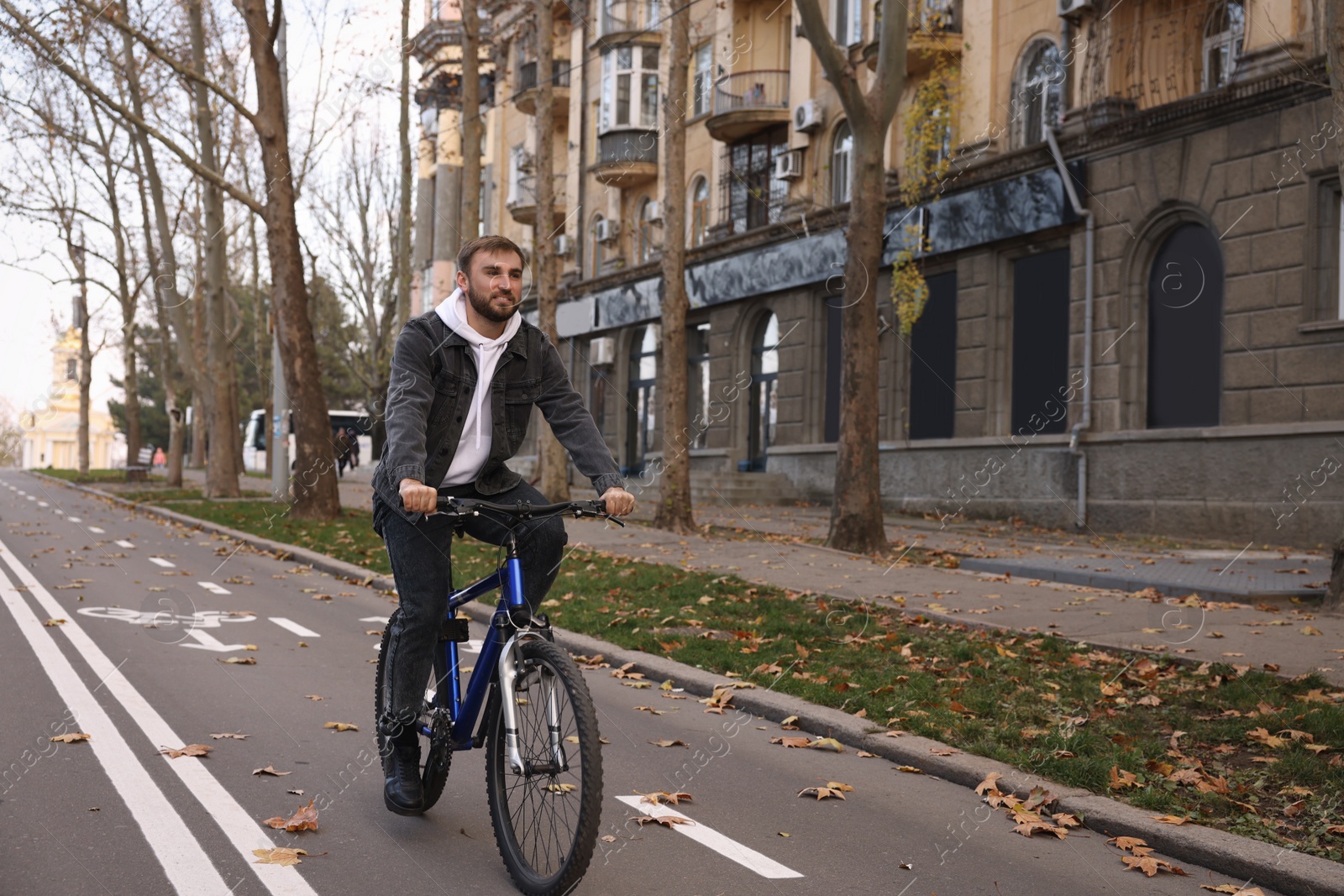 Photo of Happy handsome man riding bicycle on lane in city