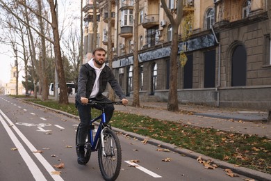 Happy handsome man riding bicycle on lane in city