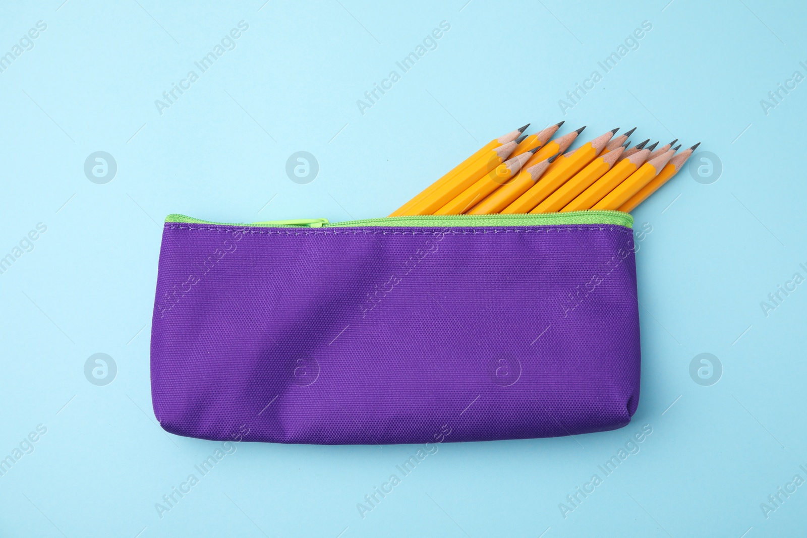 Photo of Many sharp pencils in pencil case on light blue background, top view