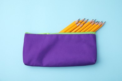 Photo of Many sharp pencils in pencil case on light blue background, top view