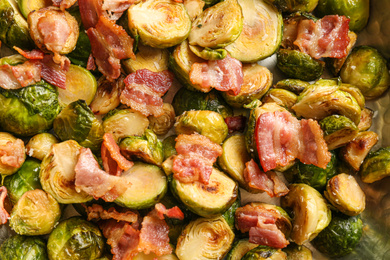 Delicious roasted Brussels sprouts with bacon as background, closeup