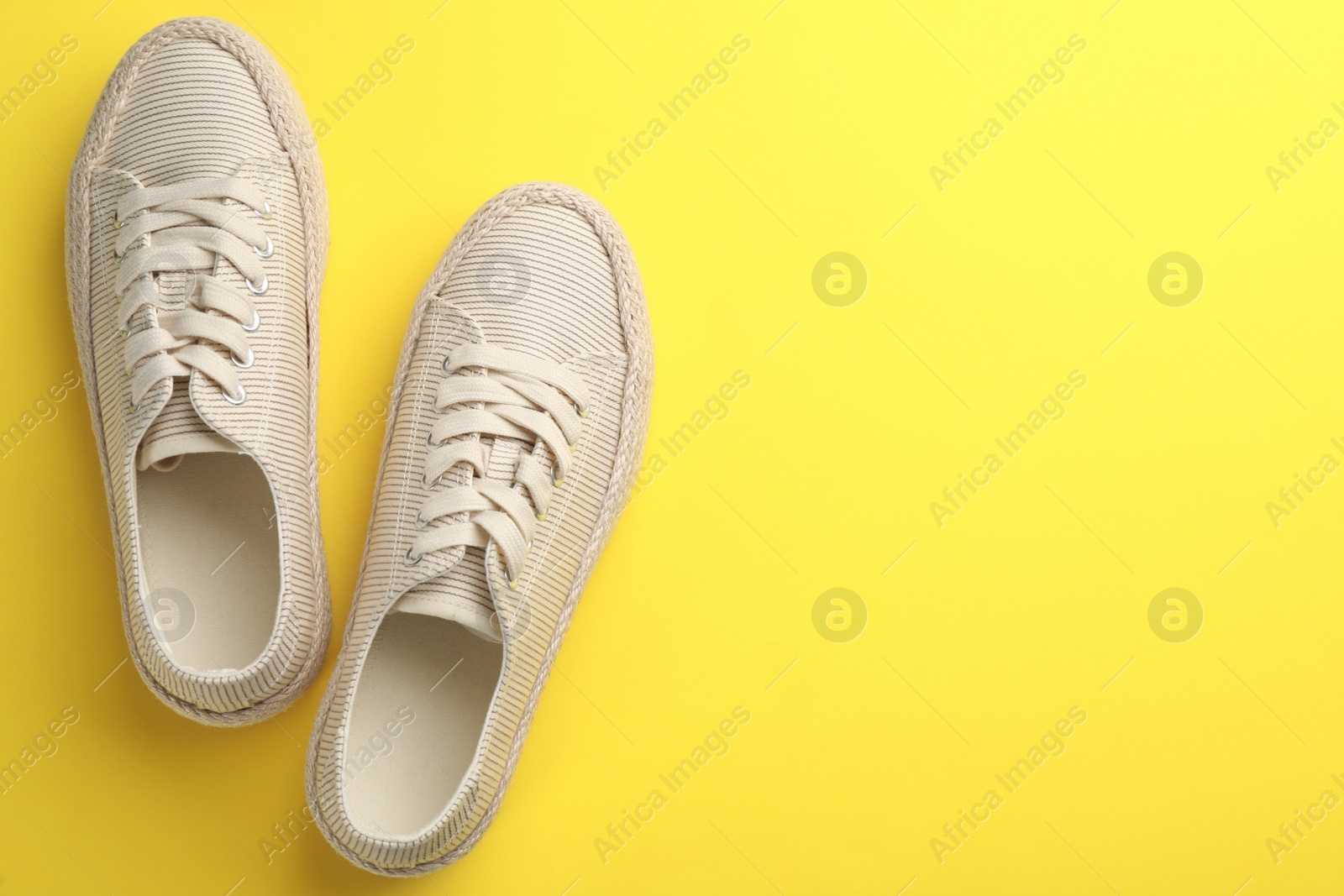 Photo of Pair of stylish comfortable shoes on yellow background, flat lay. Space for text