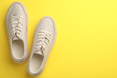 Photo of Pair of stylish comfortable shoes on yellow background, flat lay. Space for text