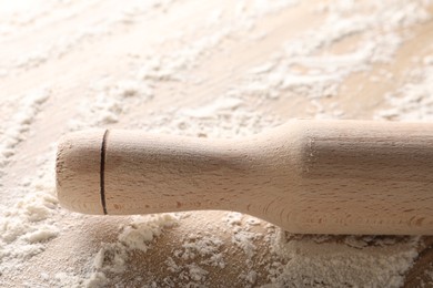 Photo of Scattered flour and rolling pin on wooden table, closeup