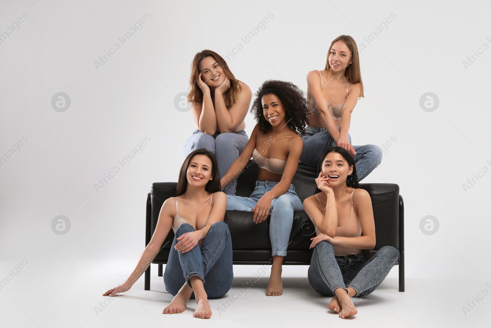 Photo of Group of women with different body types in jeans and underwear on light background