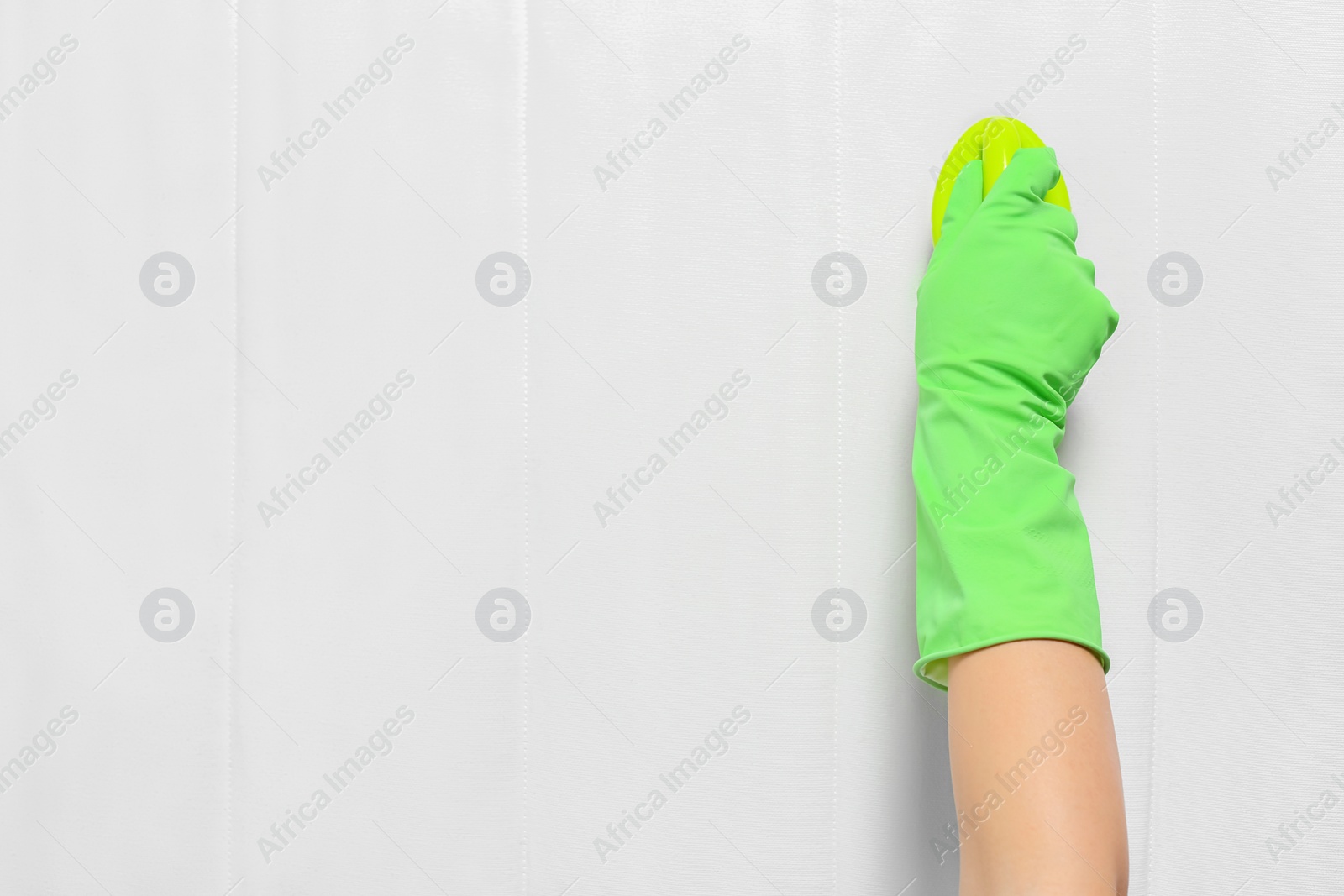 Photo of Woman in green gloves cleaning white mattress with brush, top view. Space for text