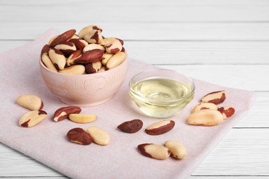 Photo of Tasty Brazil nuts and oil on white wooden table