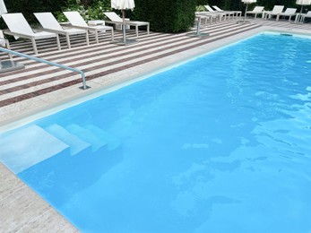 Photo of Outdoor swimming pool in luxury hotel on sunny summer day, above view. Time for relax