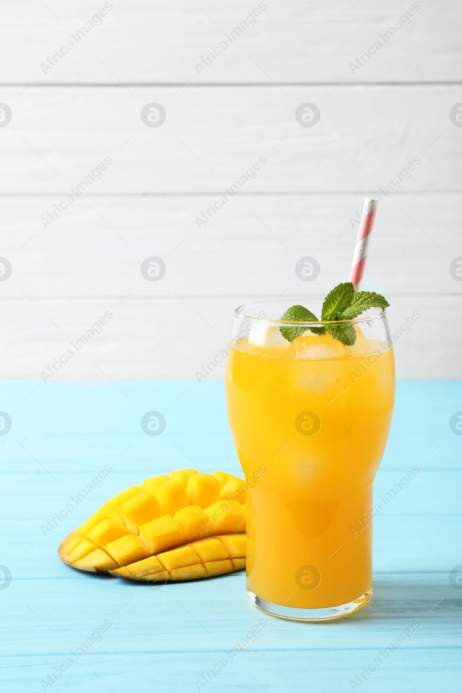 Photo of Fresh mango drink and cut fruit on blue wooden table. Space for text